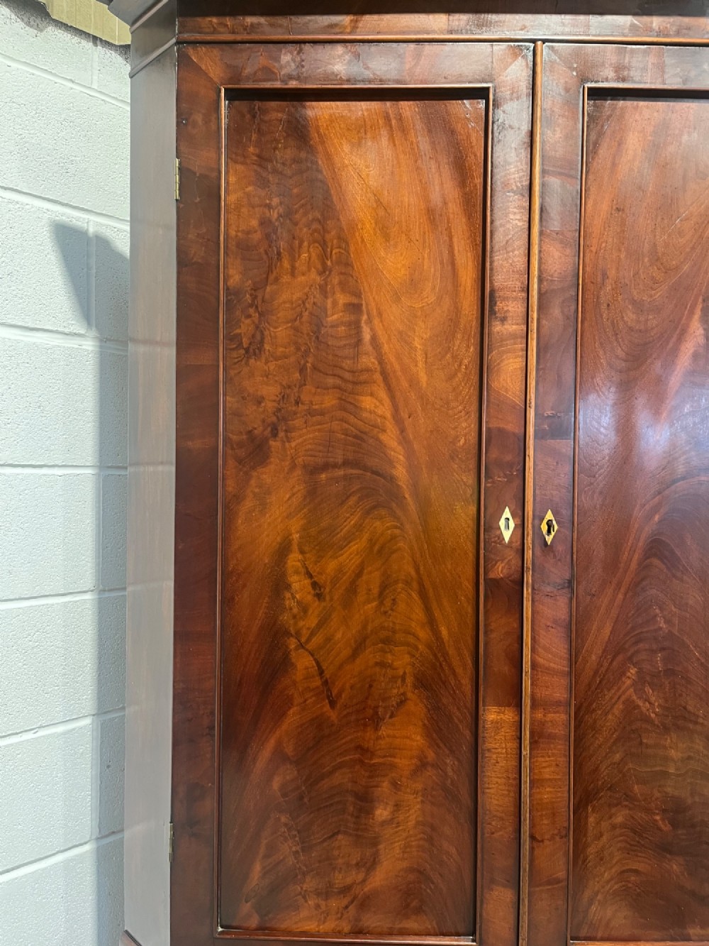 A tall Georgian floor-standing corner cupboard made of dark flame mahogany, featuring two upper doors and two lower doors with brass diamond escutcheons. View VII