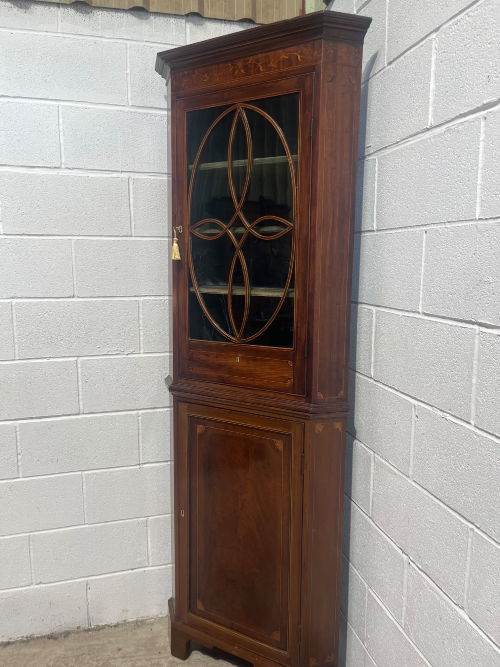 A 19th-century floor-standing mahogany corner cupboard featuring a glazed upper door with oval astragal glazing and an inlaid lower cabinet door. View II