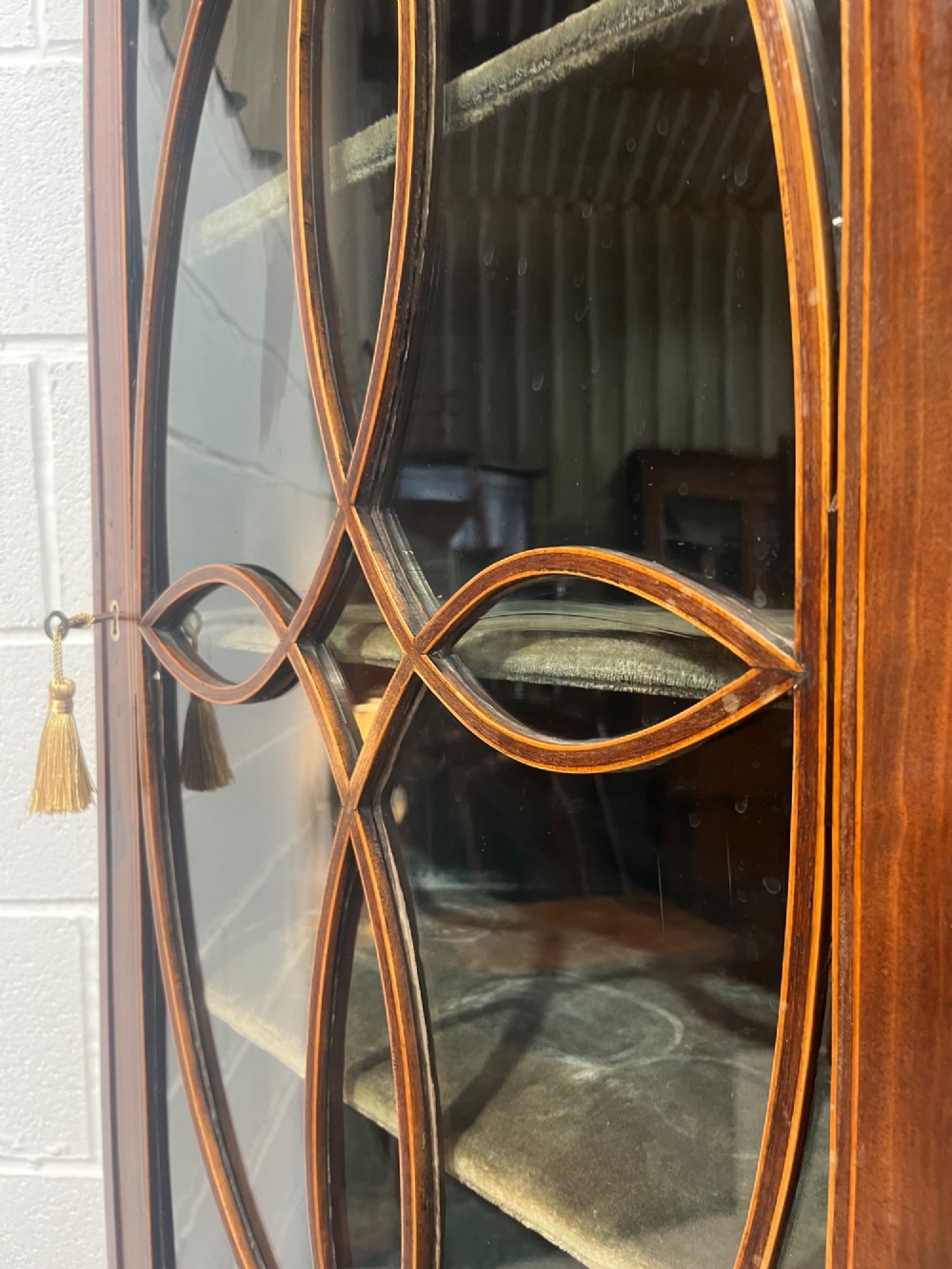 A 19th-century floor-standing mahogany corner cupboard featuring a glazed upper door with oval astragal glazing and an inlaid lower cabinet door. View V