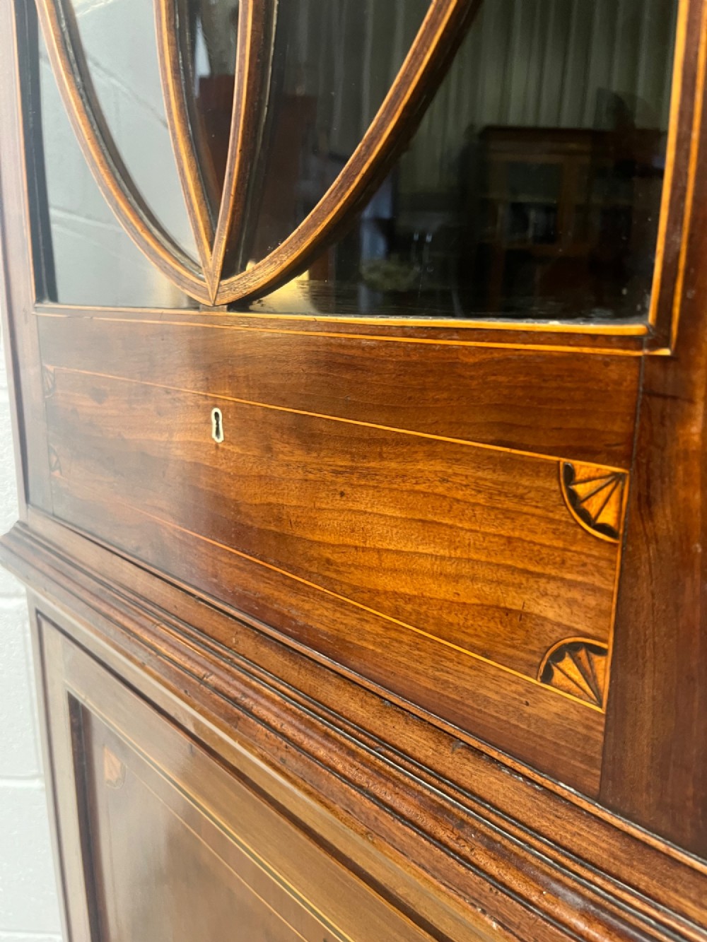 A 19th-century floor-standing mahogany corner cupboard featuring a glazed upper door with oval astragal glazing and an inlaid lower cabinet door. View VII
