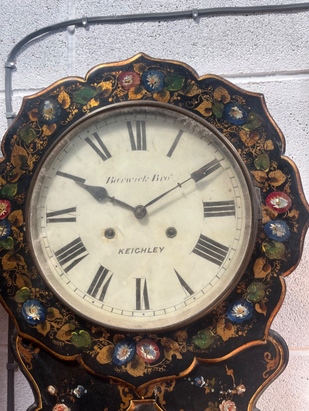 A 19th-century Victorian wall clock featuring a scalloped ebonised case decorated with gilt scrollwork and polychrome floral painting around a cream dial with Roman numerals. View VII