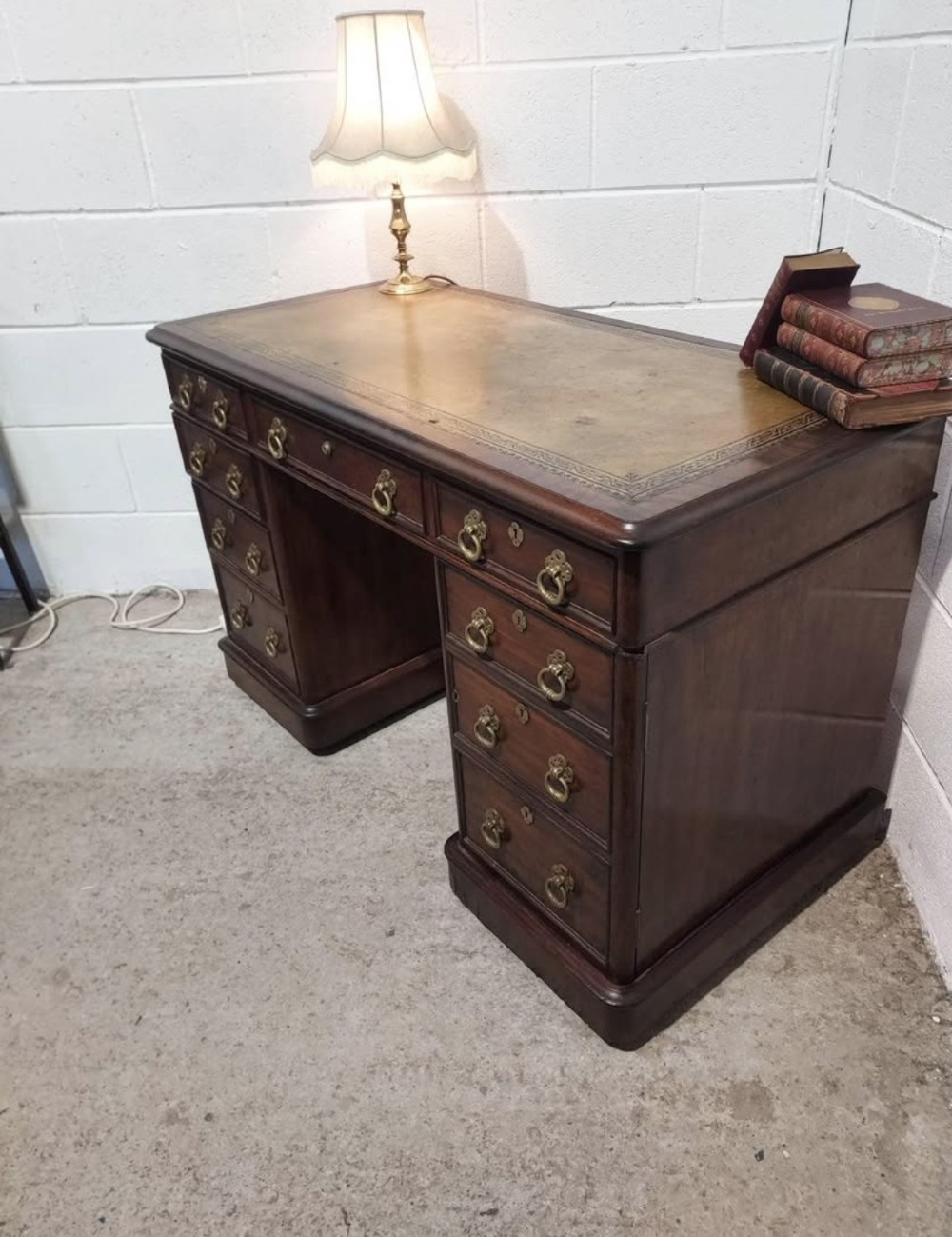 A 19th-century dark mahogany pedestal desk with multiple drawers featuring brass ring handles and a plinth base. View II