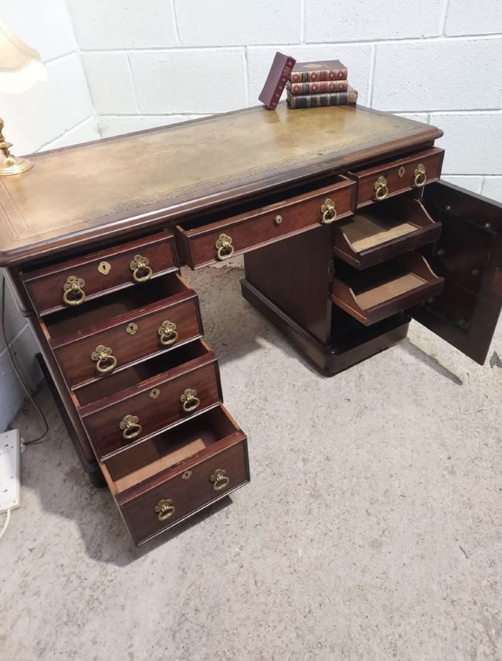 A 19th-century dark mahogany pedestal desk with multiple drawers featuring brass ring handles and a plinth base. View V