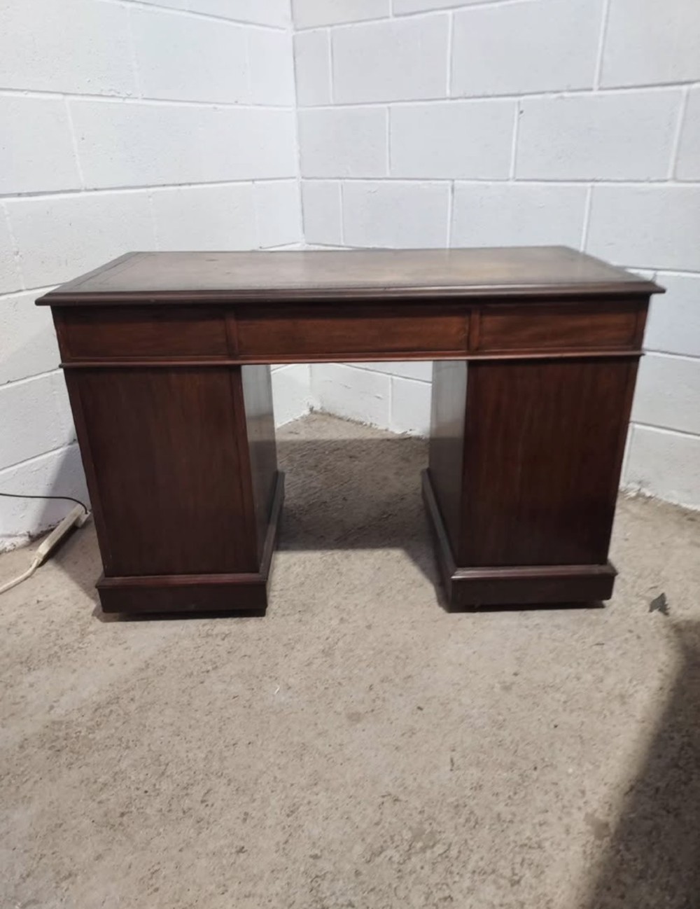 A 19th-century dark mahogany pedestal desk with multiple drawers featuring brass ring handles and a plinth base. View VIII