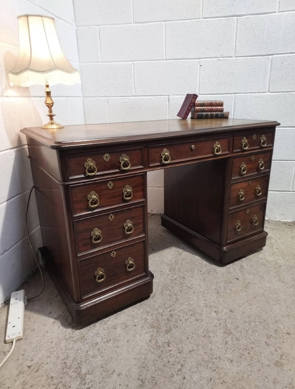 A 19th-century dark mahogany pedestal desk with multiple drawers featuring brass ring handles and a plinth base. View IX