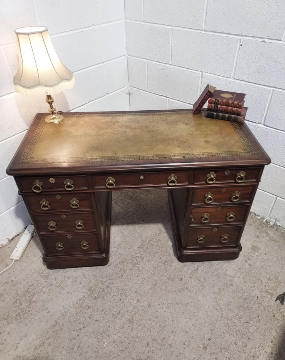 A 19th-century dark mahogany pedestal desk with multiple drawers featuring brass ring handles and a plinth base. View X