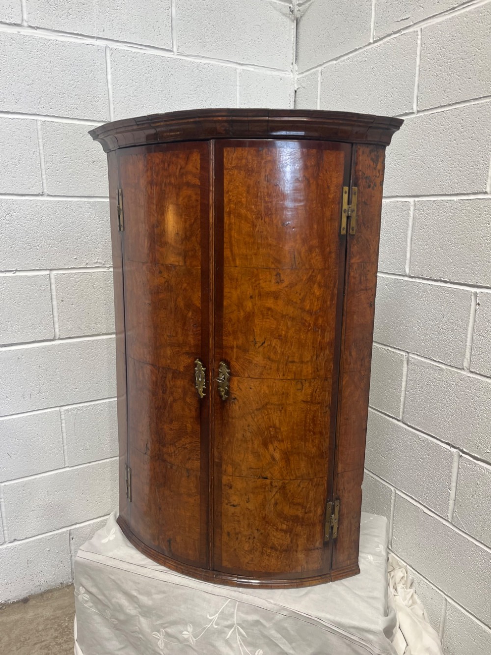 A George III bowfront corner cupboard crafted from figured burr oak timber featuring double doors with brass H-hinges. View VI