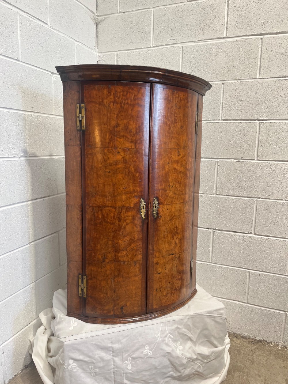 A George III bowfront corner cupboard crafted from figured burr oak timber featuring double doors with brass H-hinges. View VII