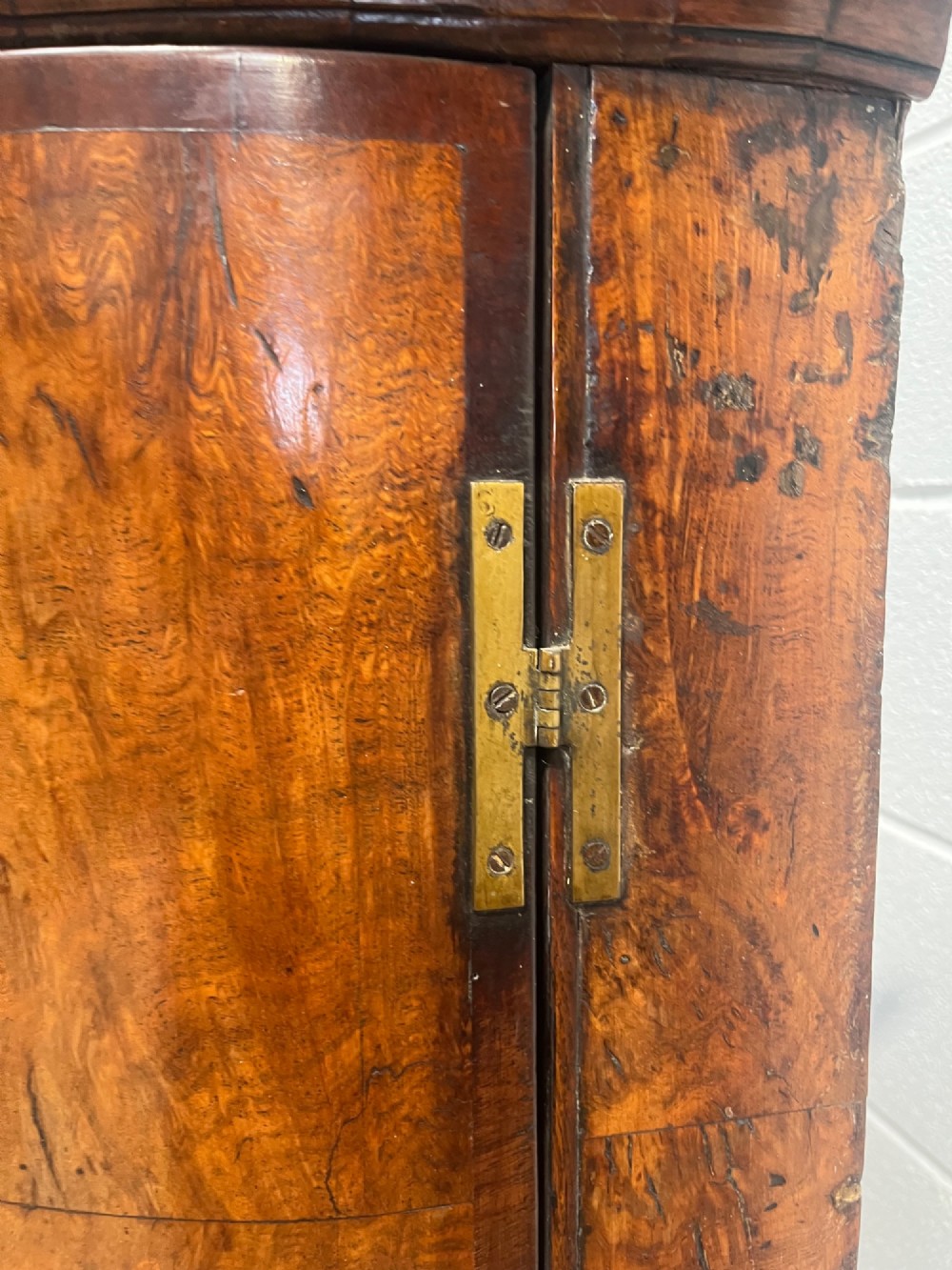 A George III bowfront corner cupboard crafted from figured burr oak timber featuring double doors with brass H-hinges. View VIII