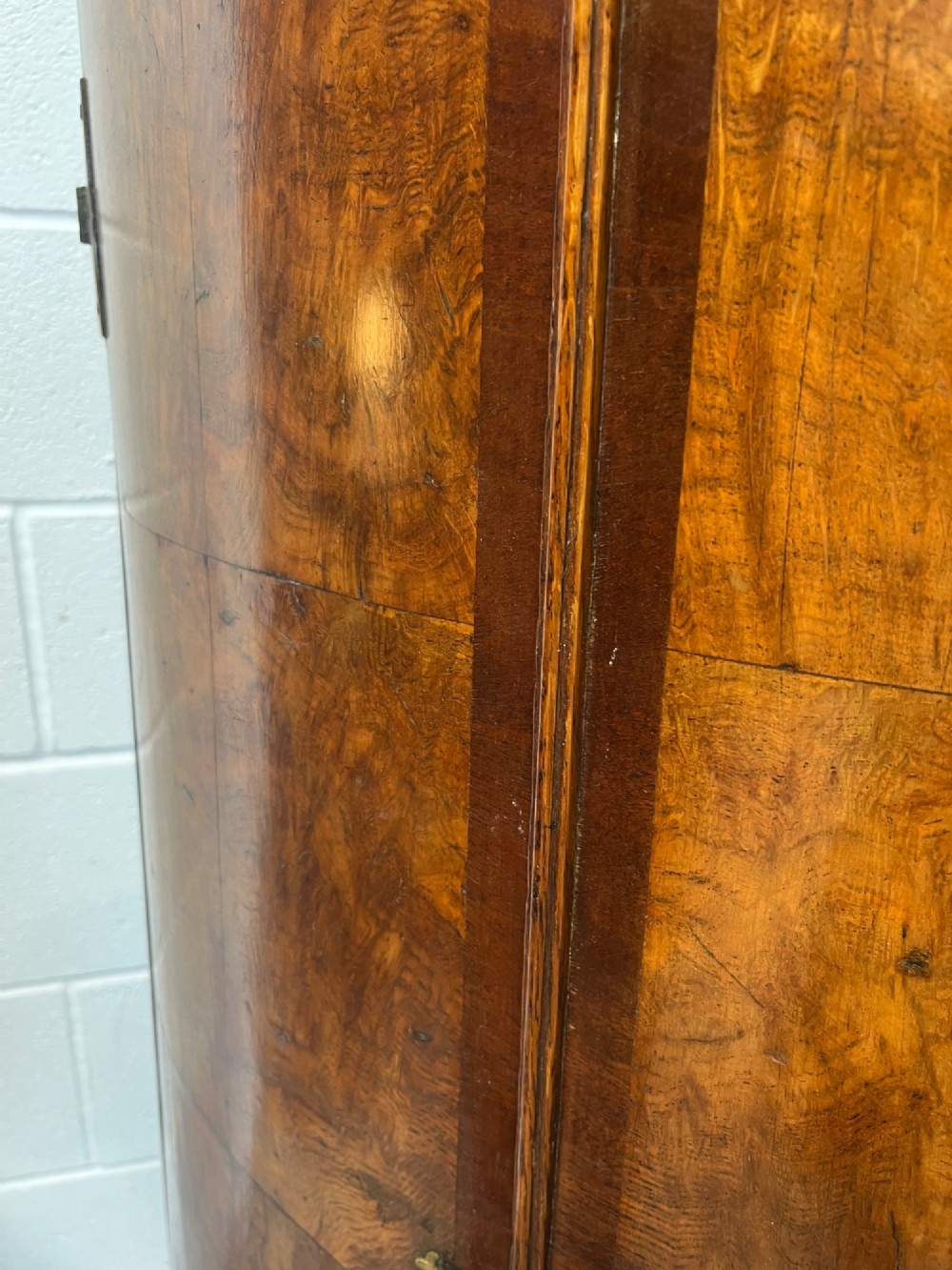A George III bowfront corner cupboard crafted from figured burr oak timber featuring double doors with brass H-hinges. View X