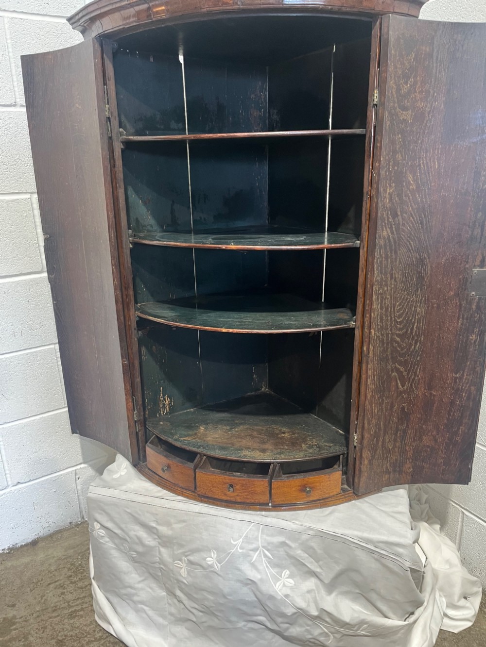 A George III bowfront corner cupboard crafted from figured burr oak timber featuring double doors with brass H-hinges. View XII