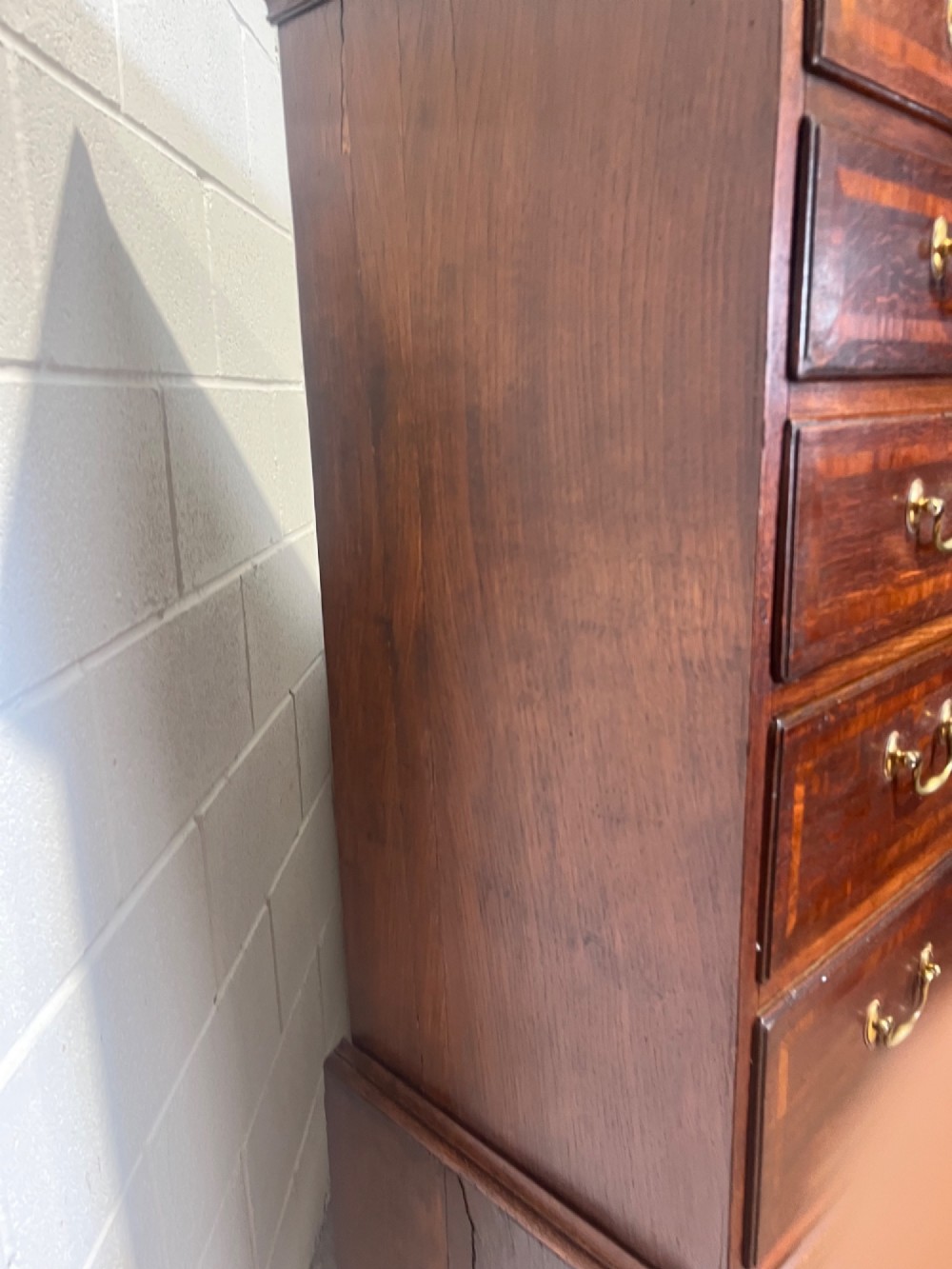 A tall George III oak chest on chest featuring brass swan-neck handles, crossbanded drawer borders, and bracket feet. View X