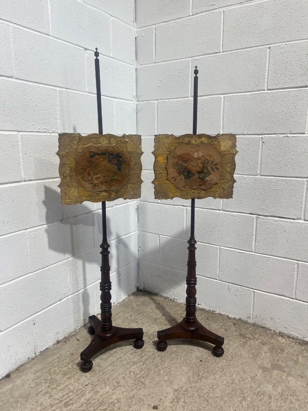 A pair of antique Regency mahogany pole screens with turned central spindles, tripod bases, and rectangular adjustable panels featuring floral paintings surrounded by gilded borders. View II