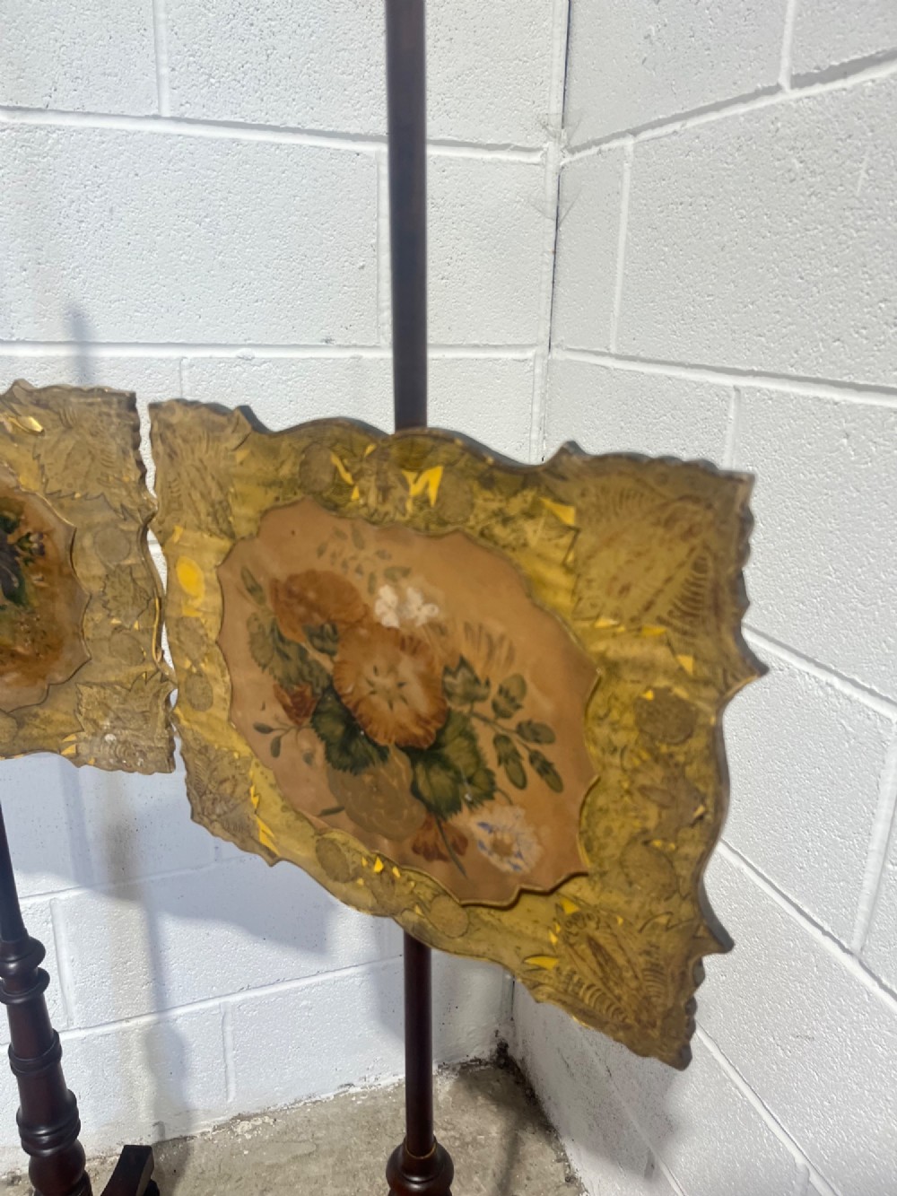 A pair of antique Regency mahogany pole screens with turned central spindles, tripod bases, and rectangular adjustable panels featuring floral paintings surrounded by gilded borders. View VI