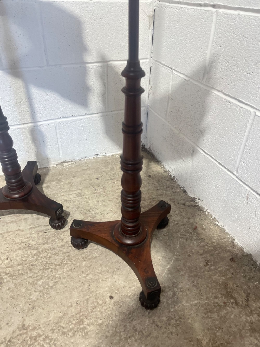 A pair of antique Regency mahogany pole screens with turned central spindles, tripod bases, and rectangular adjustable panels featuring floral paintings surrounded by gilded borders. View IX