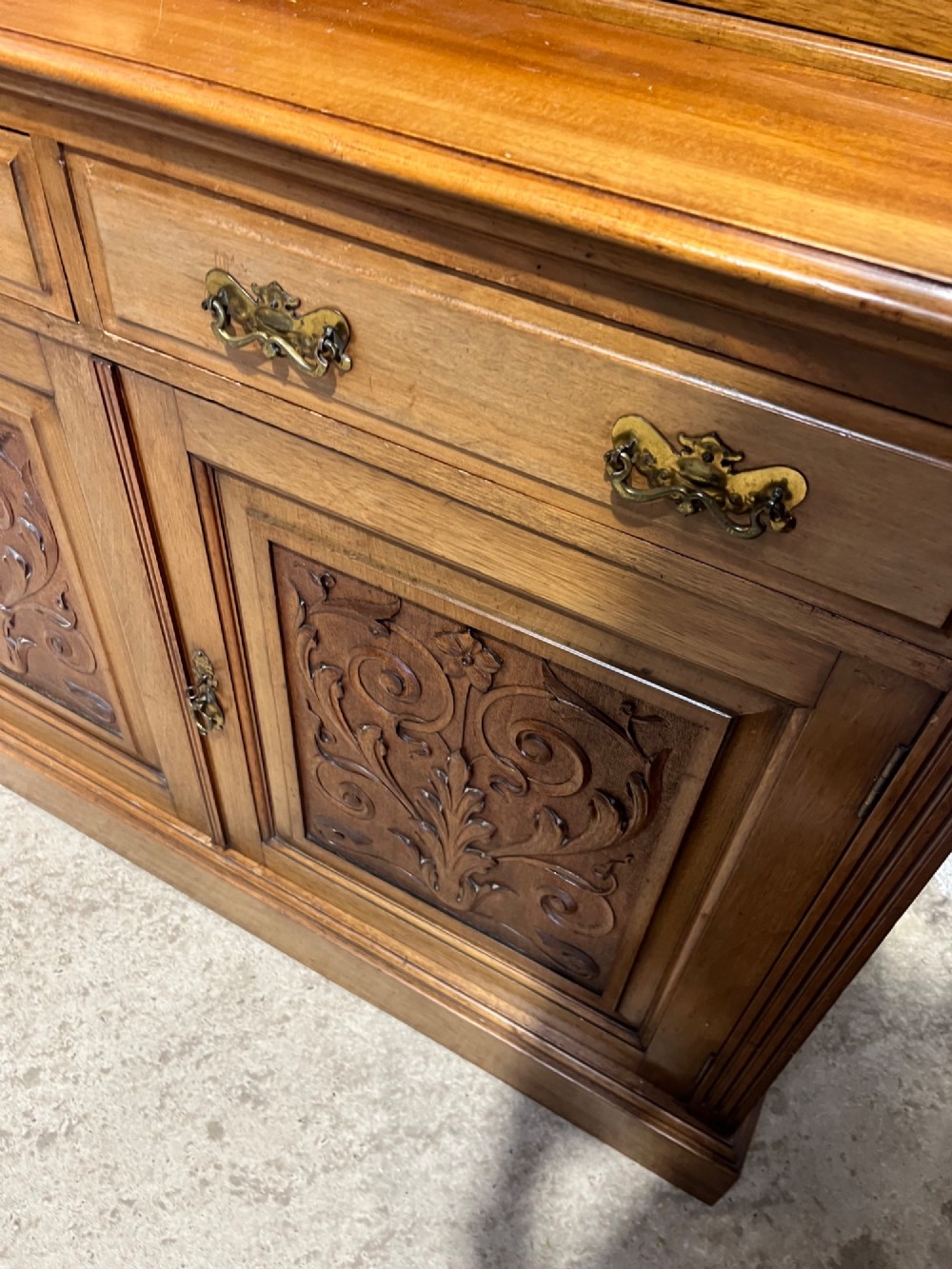 A 19th-century mahogany glazed bookcase featuring upper double glass doors filled with books, middle drawers, and lower doors with carved foliate panels. View VI