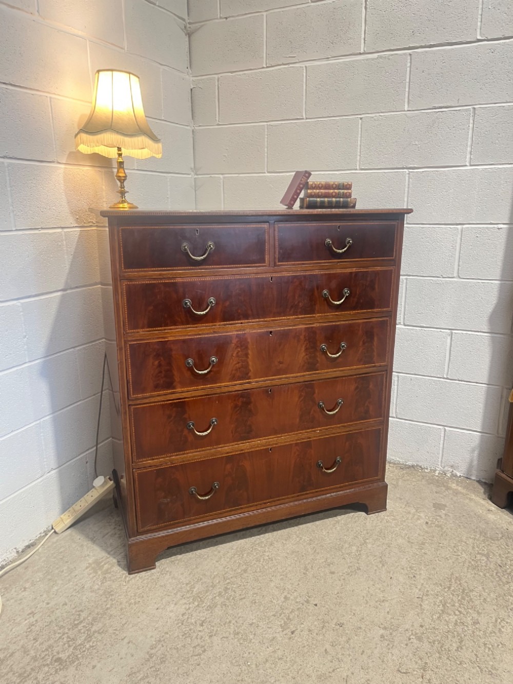 A late 19th-century mahogany chest of drawers featuring two short upper drawers over four long drawers, detailed with satinwood stringing and brass handles. View V
