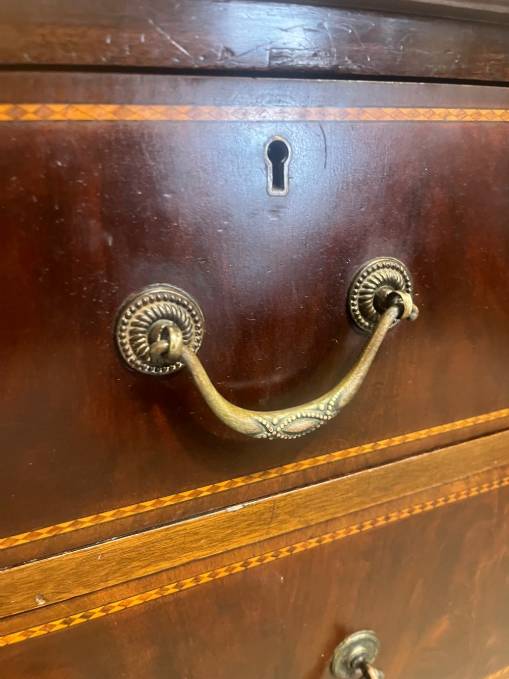 A late 19th-century mahogany chest of drawers featuring two short upper drawers over four long drawers, detailed with satinwood stringing and brass handles. View X