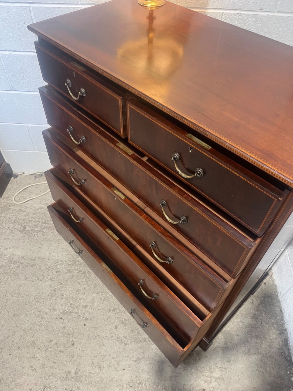 A late 19th-century mahogany chest of drawers featuring two short upper drawers over four long drawers, detailed with satinwood stringing and brass handles. View XIII