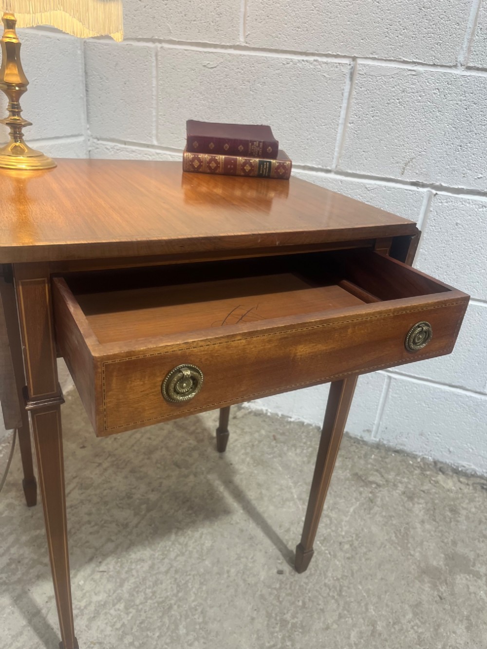 A 19th-century mahogany side table featuring two hinged drop leaves, a single frieze drawer with dual brass ring handles, boxwood line inlay, and four square tapered legs. View VI