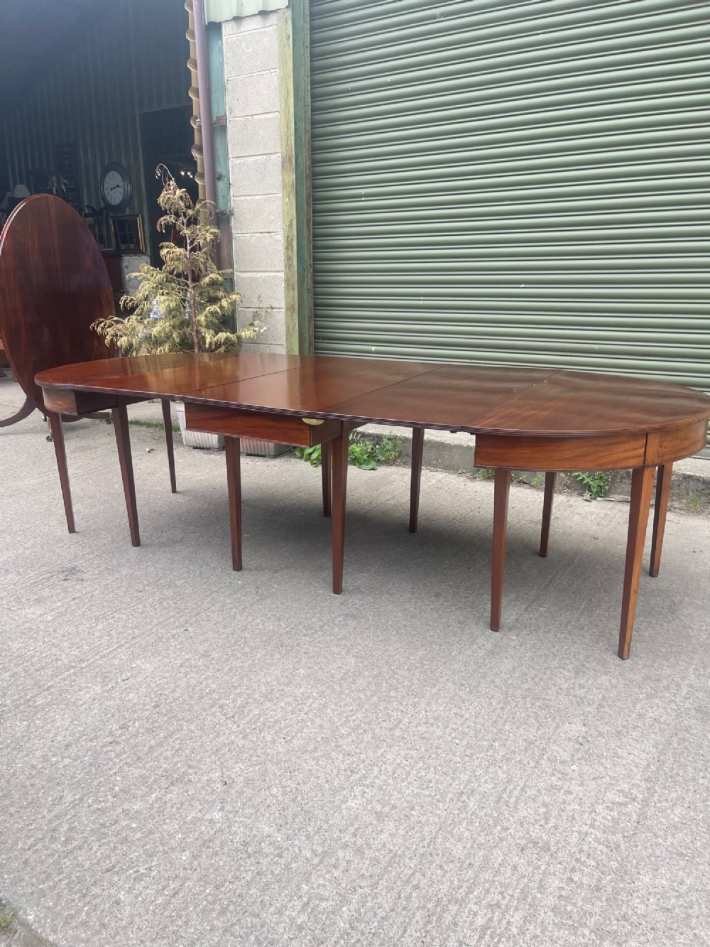 An extended 19th-century mahogany D-end dining table supported by multiple square tapered legs.