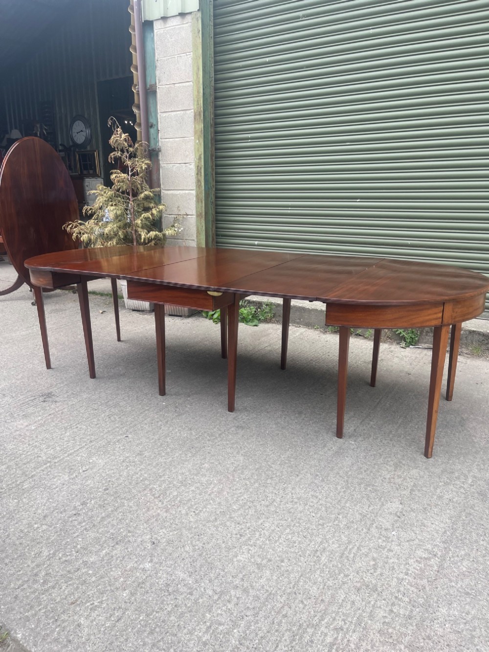 An extended 19th-century mahogany D-end dining table supported by multiple square tapered legs. View II