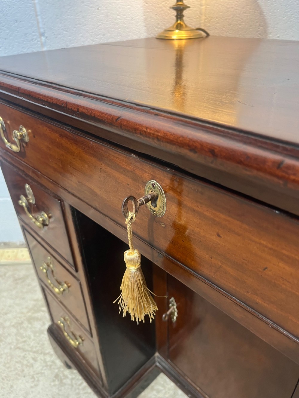 A George III mahogany kneehole desk with a full-width upper drawer over six side drawers, a central recessed cupboard, brass swan-neck handles, and bracket feet. View IX