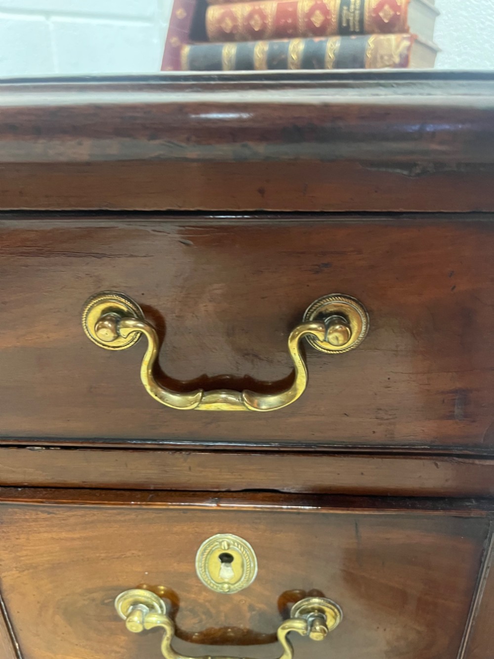 A George III mahogany kneehole desk with a full-width upper drawer over six side drawers, a central recessed cupboard, brass swan-neck handles, and bracket feet. View X