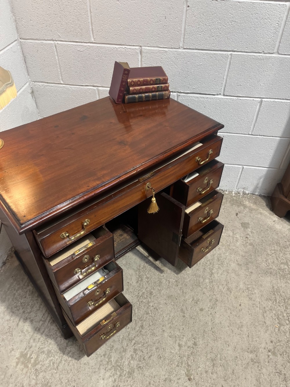 A George III mahogany kneehole desk with a full-width upper drawer over six side drawers, a central recessed cupboard, brass swan-neck handles, and bracket feet. View XII