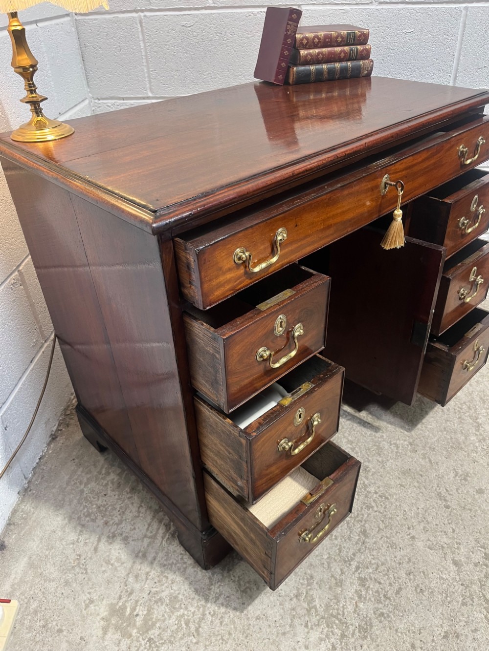 A George III mahogany kneehole desk with a full-width upper drawer over six side drawers, a central recessed cupboard, brass swan-neck handles, and bracket feet. View XIII
