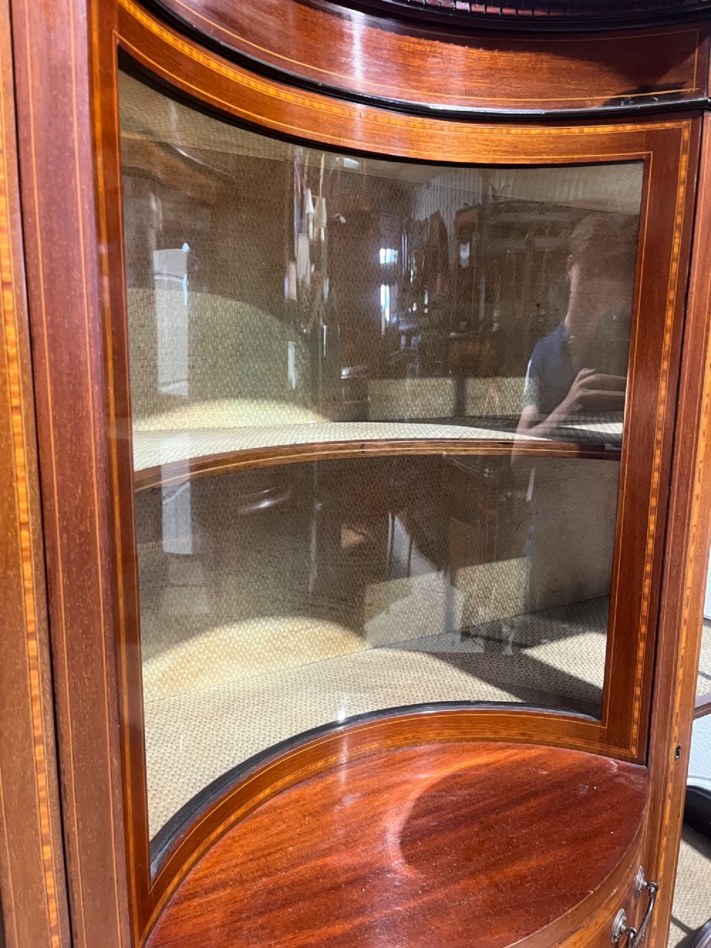 An antique inlaid mahogany display cabinet featuring a concave glazed central section, satinwood marquetry swags, astragal glazing bars, and tapered square legs. View IX