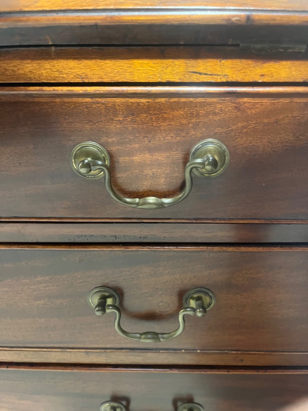 A Georgian mahogany writing bureau with an open sloped lid revealing internal fitted pigeonholes and small drawers above three wide drawers with brass handles. View VII