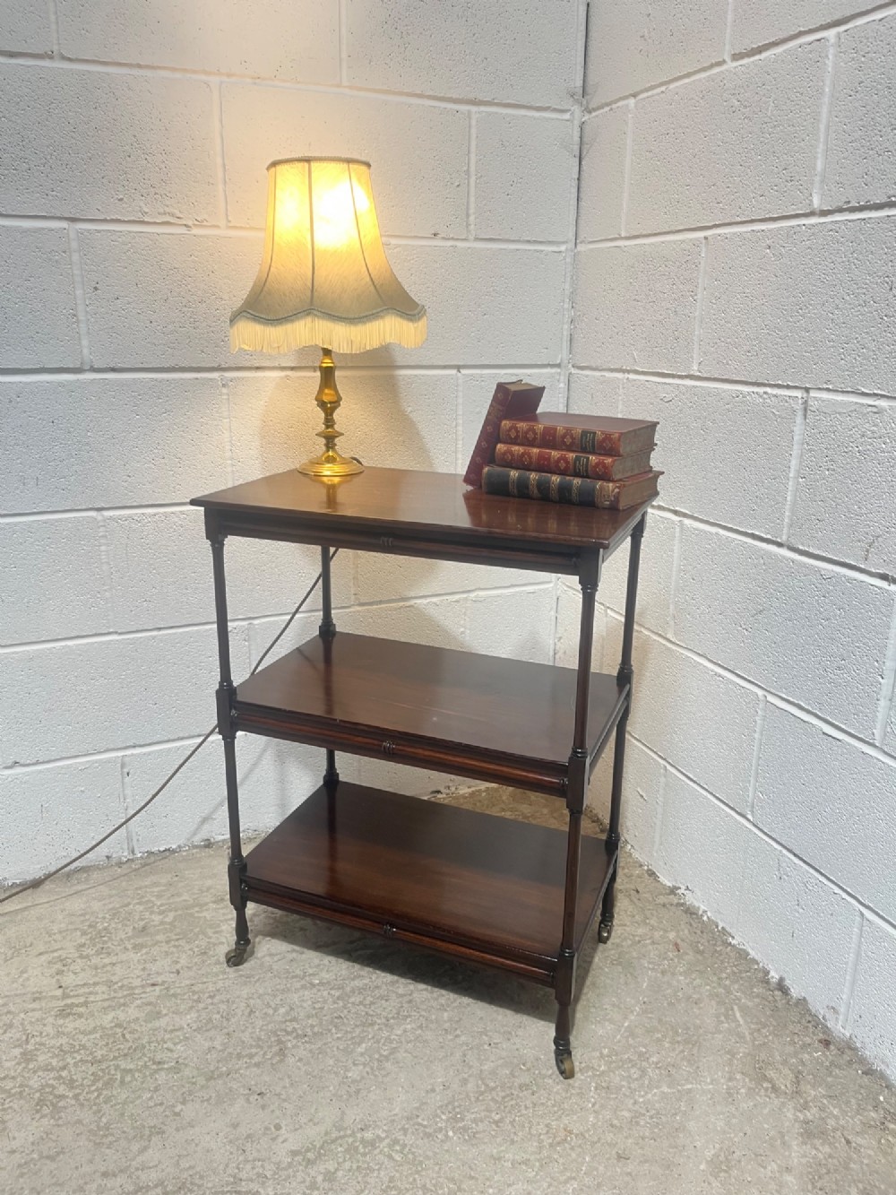 A nineteenth-century dark mahogany three-tier trolley with turned support columns and castor wheels. View II