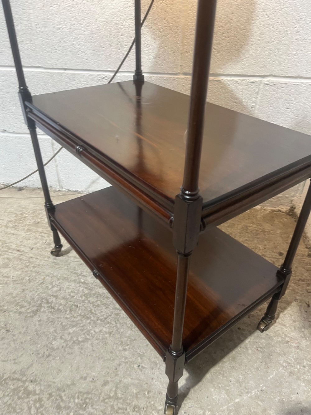 A nineteenth-century dark mahogany three-tier trolley with turned support columns and castor wheels. View VI