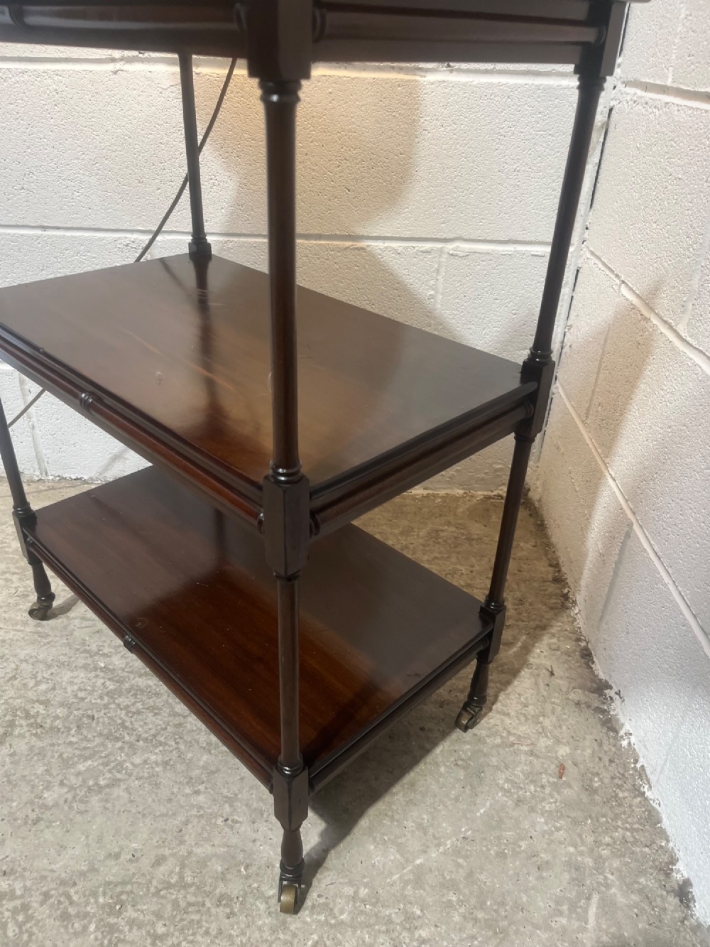 A nineteenth-century dark mahogany three-tier trolley with turned support columns and castor wheels. View VII