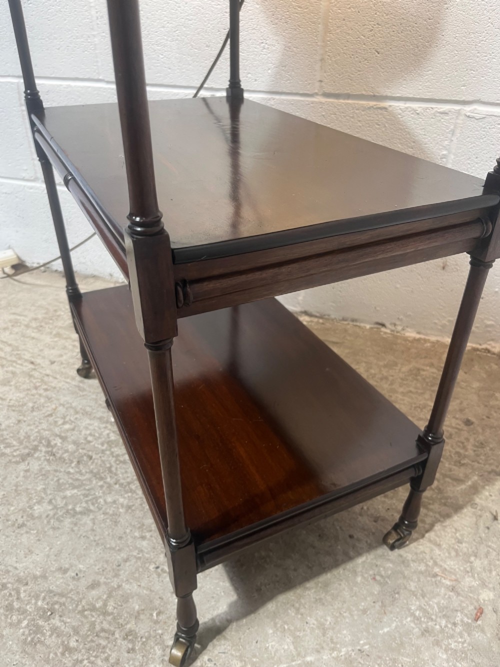 A nineteenth-century dark mahogany three-tier trolley with turned support columns and castor wheels. View IX