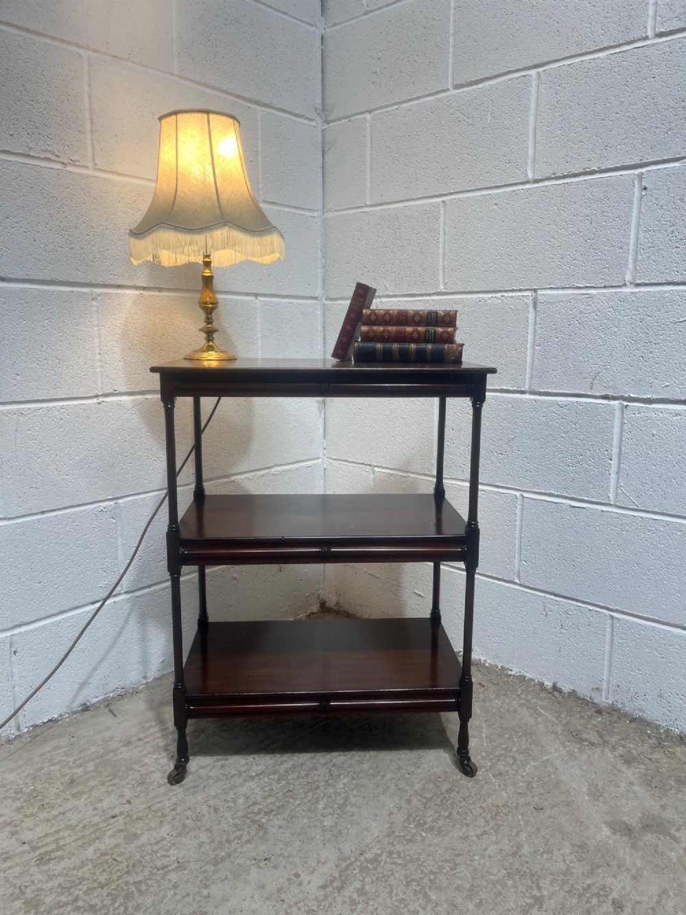 A nineteenth-century dark mahogany three-tier trolley with turned support columns and castor wheels. View XI
