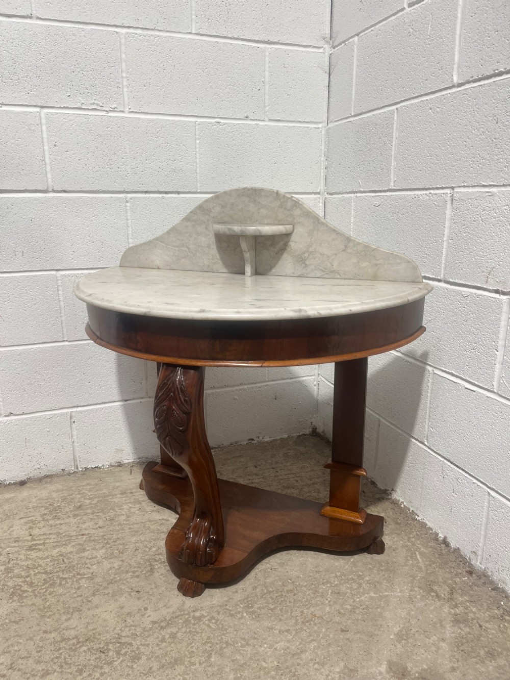 A nineteenth-century mahogany console table featuring a circular white marble top, a shaped marble splashback with an integrated shelf, and a carved central leg resting on a plinth base. View IV