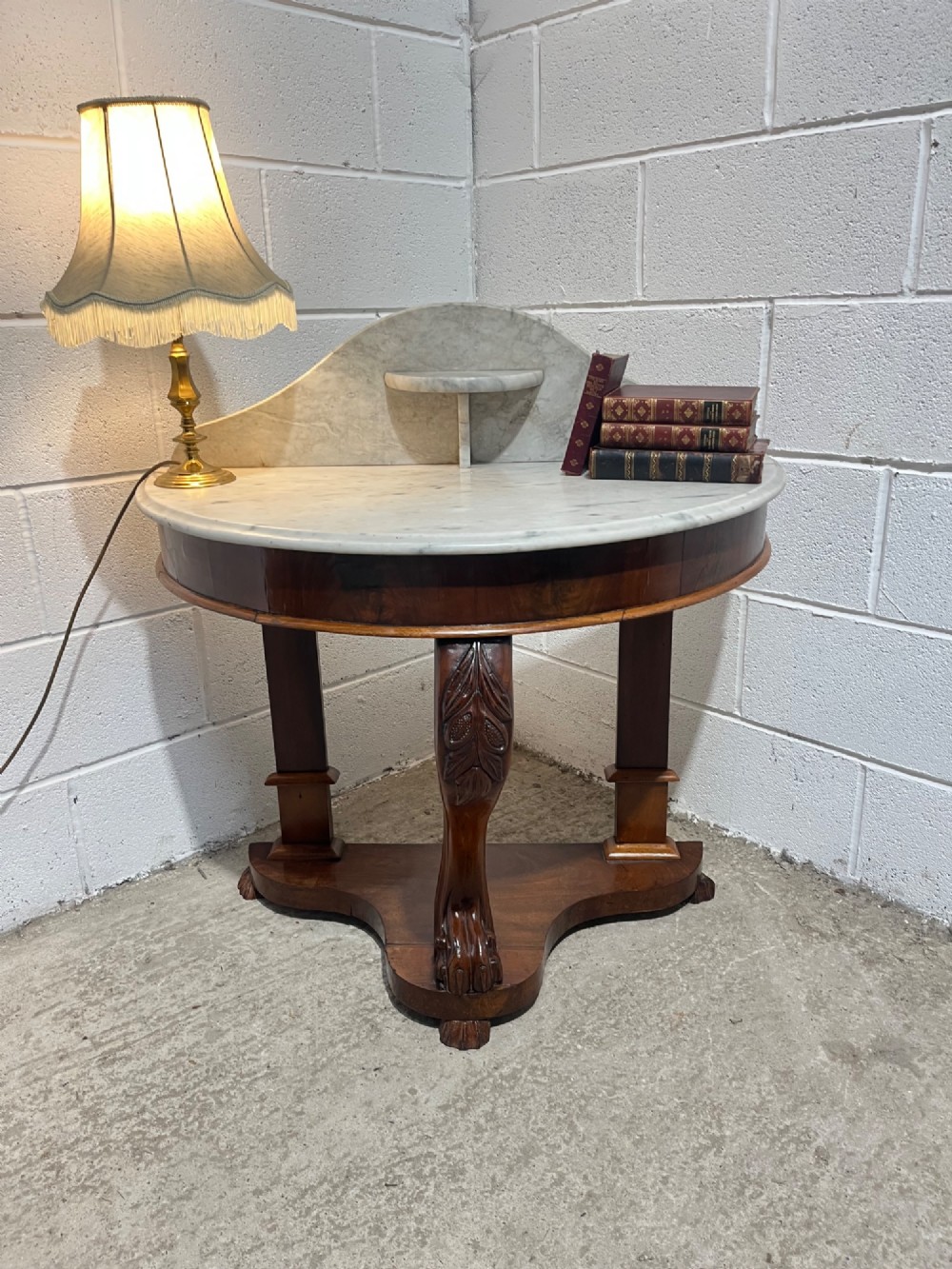 A nineteenth-century mahogany console table featuring a circular white marble top, a shaped marble splashback with an integrated shelf, and a carved central leg resting on a plinth base. View V