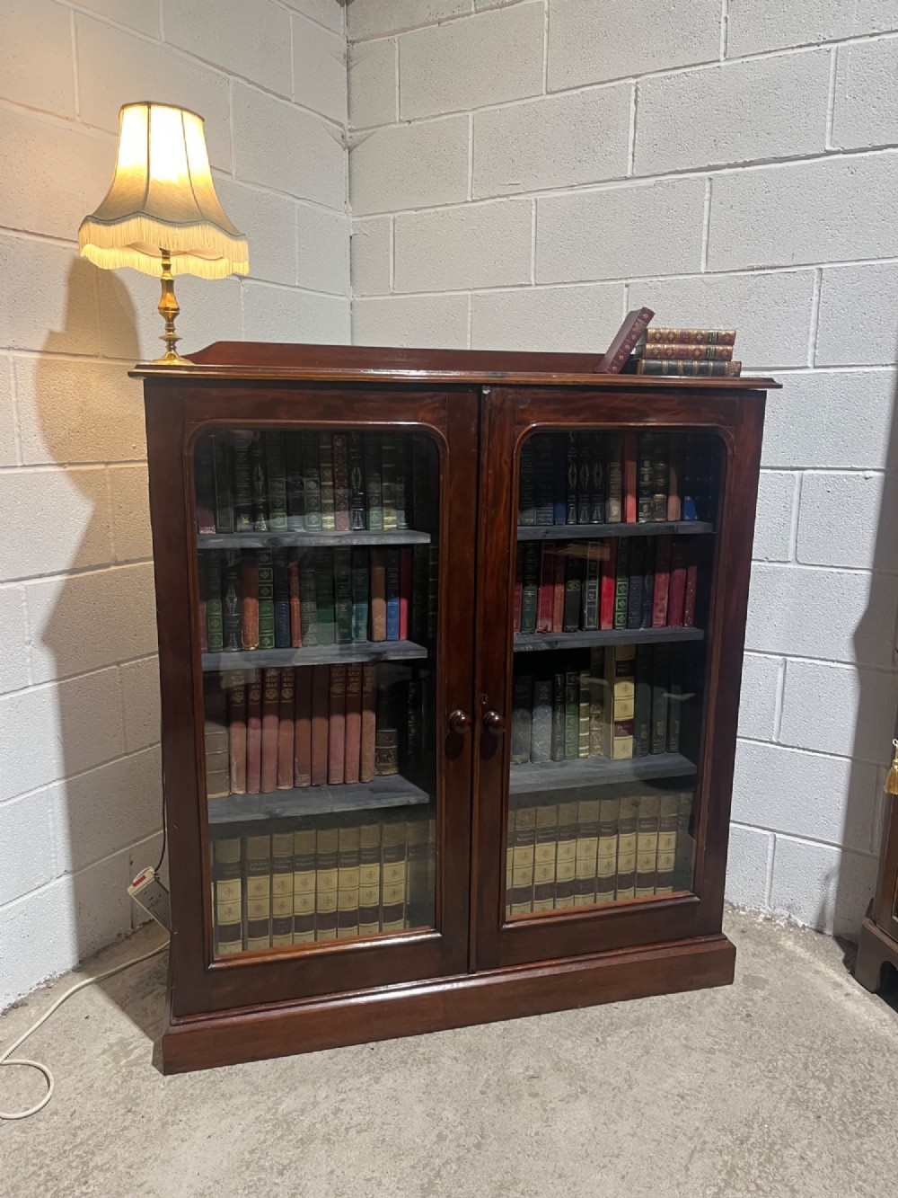 A 19th-century mahogany glazed bookcase with two glass-panelled doors revealing shelves filled with books. View II