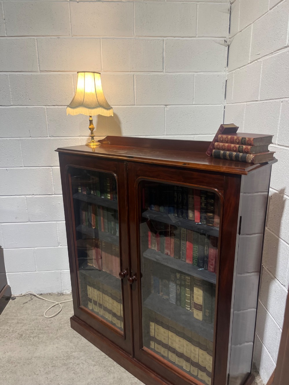 A 19th-century mahogany glazed bookcase with two glass-panelled doors revealing shelves filled with books. View V