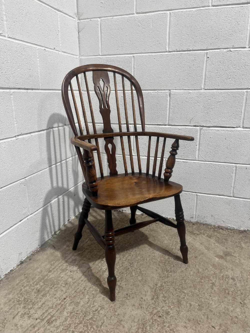 An antique 19th-century ash and elm high-back Windsor armchair featuring a hoop back with central pierced splat, turned arm supports, shaped saddle seat, and turned legs with an H-stretcher. View II