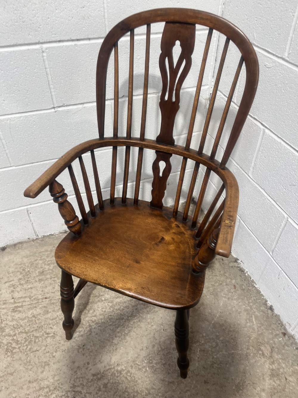 An antique 19th-century ash and elm high-back Windsor armchair featuring a hoop back with central pierced splat, turned arm supports, shaped saddle seat, and turned legs with an H-stretcher. View VI