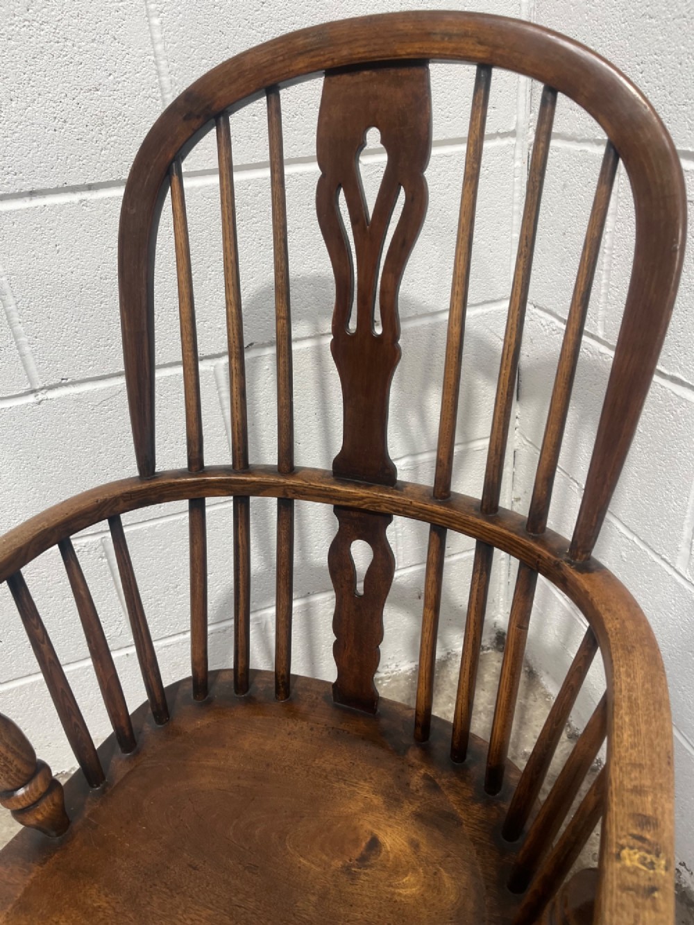An antique 19th-century ash and elm high-back Windsor armchair featuring a hoop back with central pierced splat, turned arm supports, shaped saddle seat, and turned legs with an H-stretcher. View VIII
