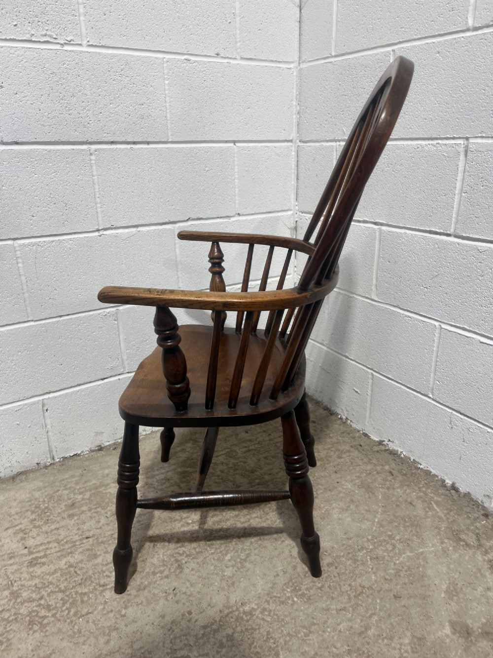An antique 19th-century ash and elm high-back Windsor armchair featuring a hoop back with central pierced splat, turned arm supports, shaped saddle seat, and turned legs with an H-stretcher. View X