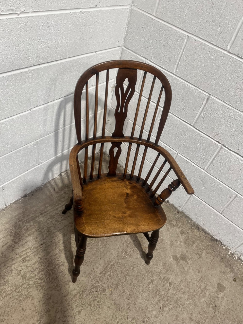 An antique 19th-century ash and elm high-back Windsor armchair featuring a hoop back with central pierced splat, turned arm supports, shaped saddle seat, and turned legs with an H-stretcher. View XII