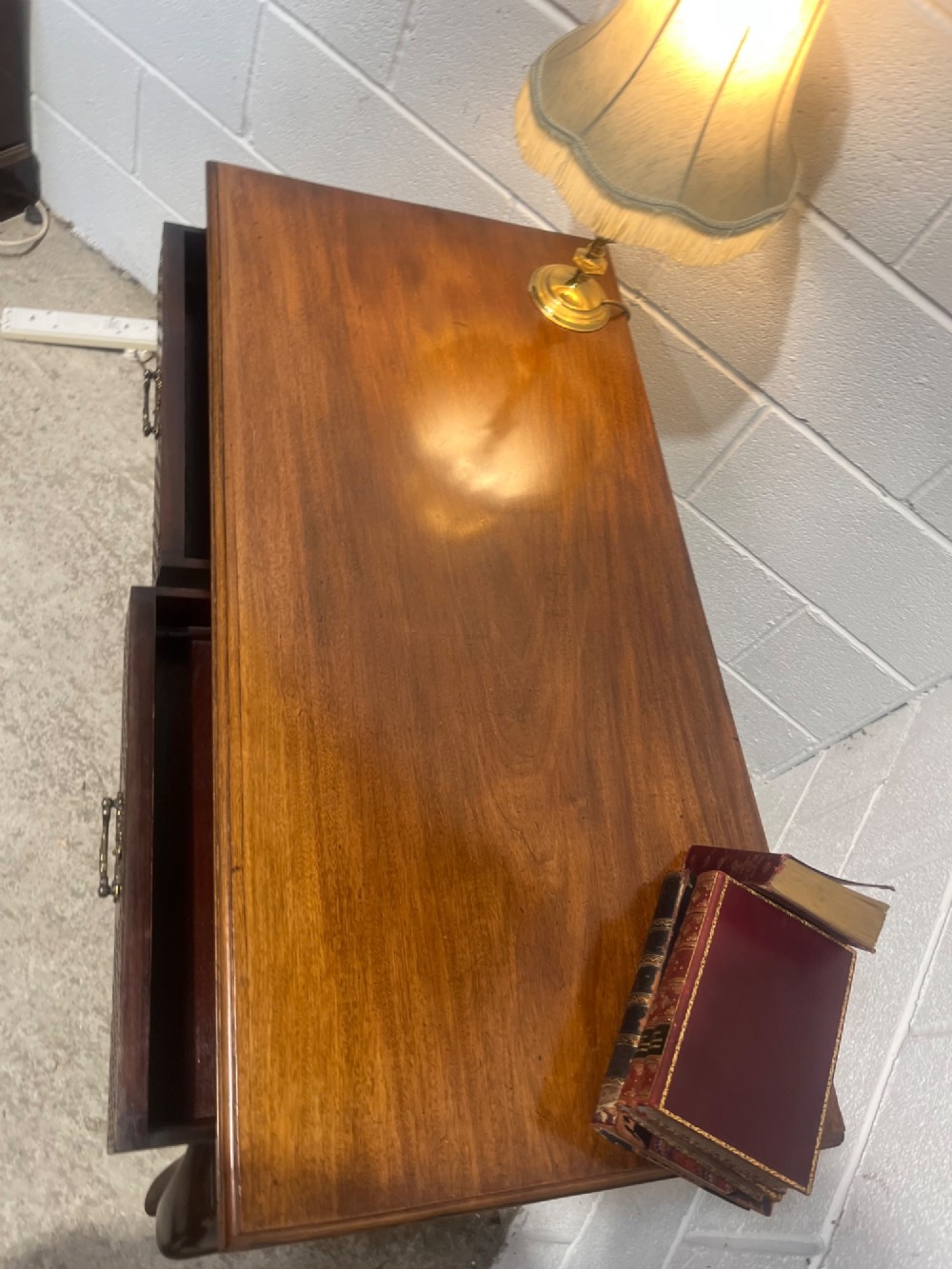 An Edwardian dark mahogany writing desk featuring two blind fretwork carved drawers with brass drop handles and slender cabriole legs on brass castors. View X