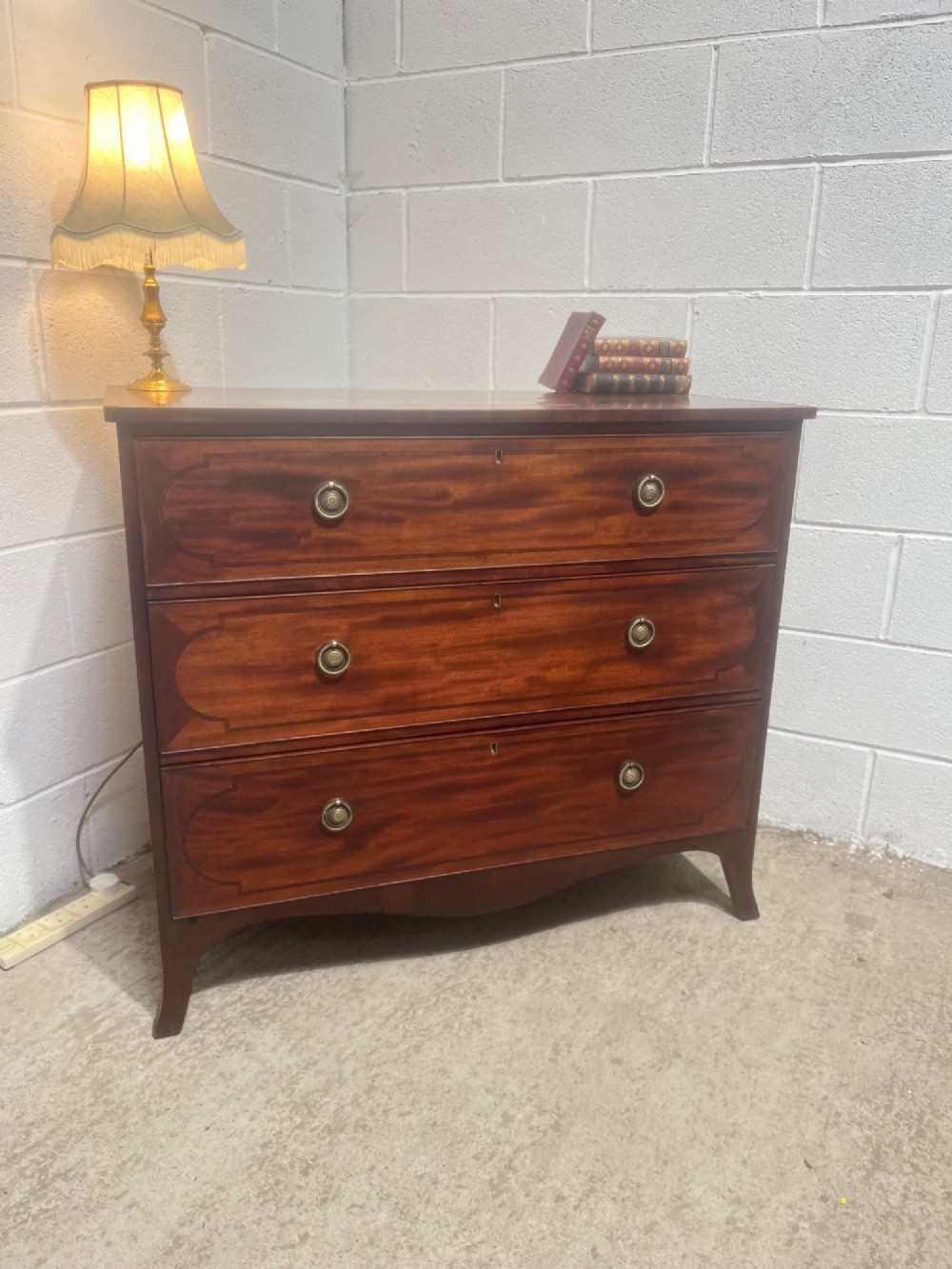 A nineteenth-century mahogany chest of three full-width drawers featuring brass ring handles, boxwood string inlay, and splayed bracket feet. View II