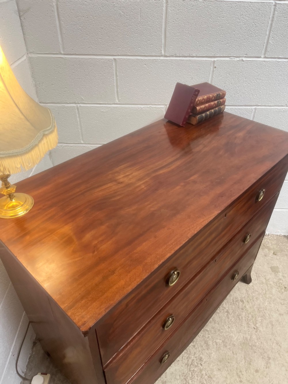 A nineteenth-century mahogany chest of three full-width drawers featuring brass ring handles, boxwood string inlay, and splayed bracket feet. View IV