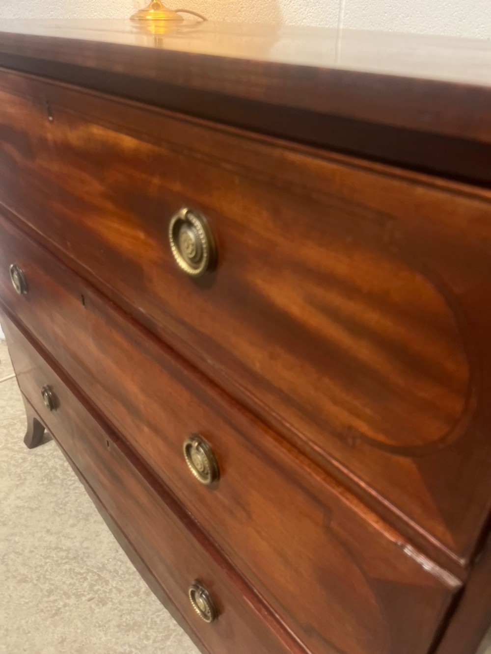 A nineteenth-century mahogany chest of three full-width drawers featuring brass ring handles, boxwood string inlay, and splayed bracket feet. View VI